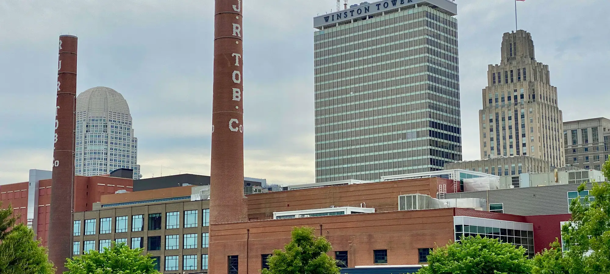 Downtown Winston-Salem skyline behind historic factory smokestacks
