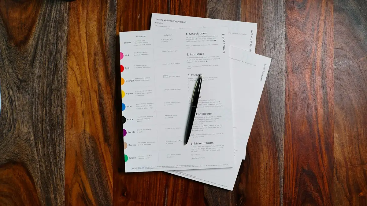 Proposal documents and a pen on a wooden desk