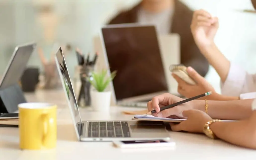 business professional working on a laptop writing notes