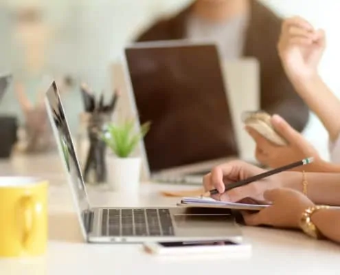 business professional working on a laptop writing notes